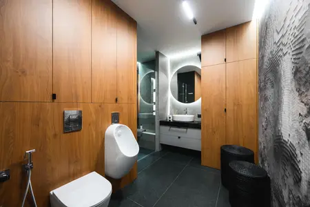 Wnętrze łazienki z drewnianymi meblami, nowoczesnymi detalami i industrialnym wykończeniem.