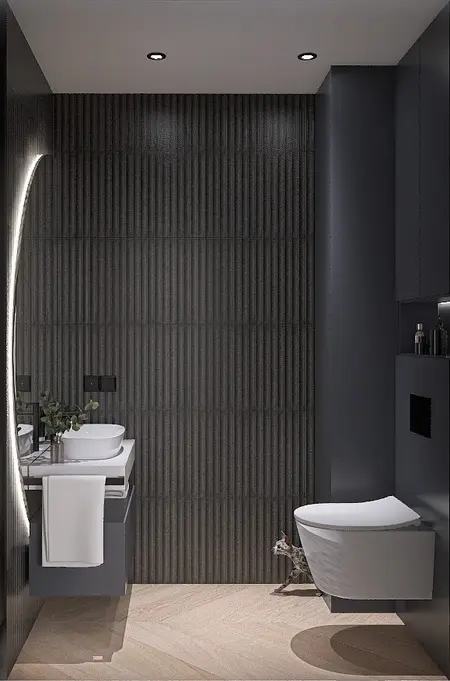 Nowoczesna łazienka z ciemnymi płytkami i białym WC oraz umywalką.