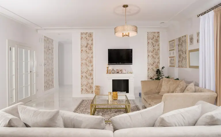 Wnętrze salonu w stylu glamour i quiet luxury z beżową sofą i ozdobnymi ścianami.