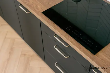 Kuchnia z drewnianym blatem i czarnymi szafkami w stylu industrialnym.