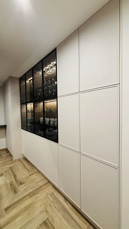 Wnętrze kuchni w stylu industrialnym z białymi meblami i drewnianą podłogą.