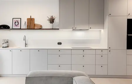 Wnętrze kuchni z szarymi meblami, białym blatem i akcentami boho, art deco i eklektycznymi.