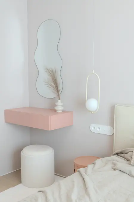 Sypialnia w stylu art deco i boho z różowym stolikiem i dekoracyjną rośliną.