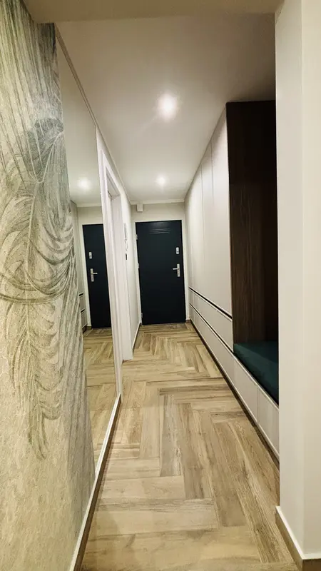 Przedpokój w stylu industrialnym i minimalistycznym z drewnianą podłogą i szafkami.