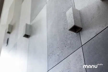 Betonowa ściana z minimalistycznym oświetleniem w industrialnym wnętrzu.