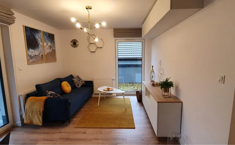 Nowoczesny salon w stylu skandynawskim z niebieską kanapą i białymi meblami.