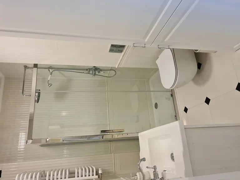 Tradycyjna łazienka z kabiną prysznicową, białymi meblami i eleganckimi akcentami.