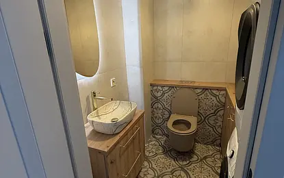 Nowoczesna łazienka w stylu boho z drewnianą szafką i dekoracyjną podłogą.
