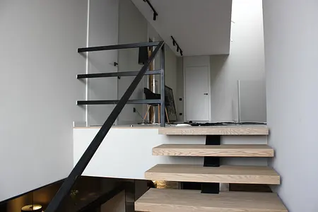 Widok wnętrza z minimalistycznymi schodami i szarymi ścianami, styl minimalistyczny, minimaluxe, nowoczesny.