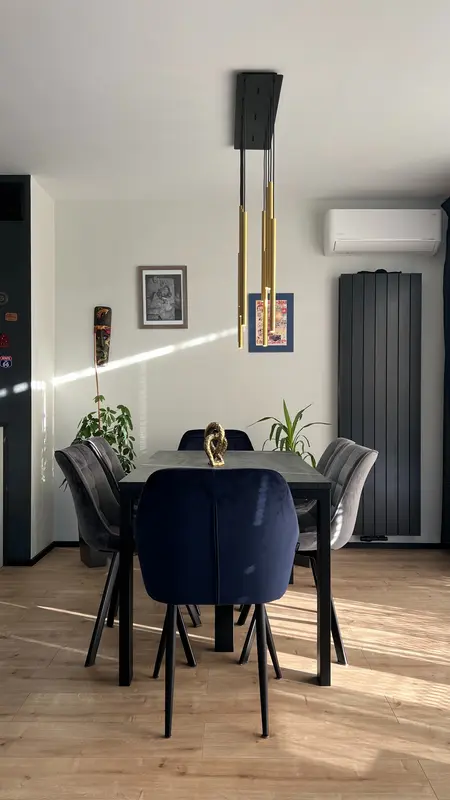 Wnętrze jadalni z niebieskimi krzesłami, drewnianym stołem, nowoczesnym oświetleniem i roślinami.