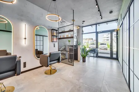 Salon fryzjerski z industrialnym wystrojem, nowoczesnymi lustrami i roślinami.