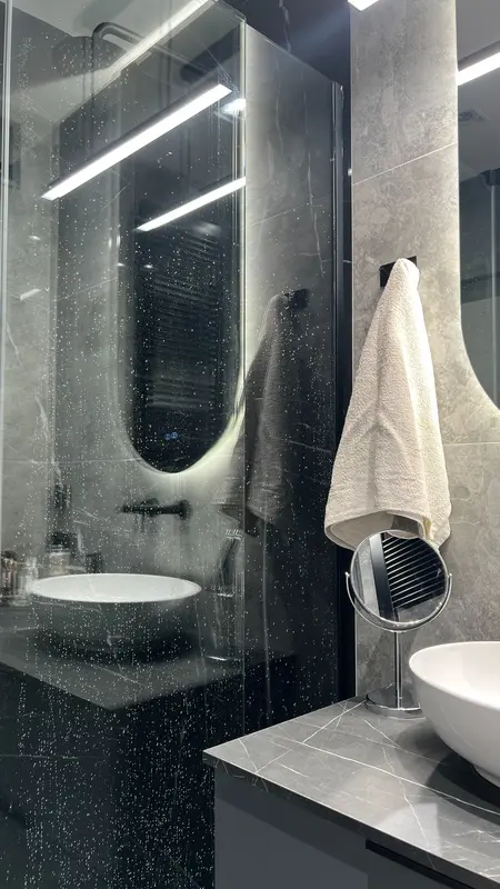 Nowoczesna łazienka w stylu soft minimalizm z szarym blatem i okrągłą umywalką.