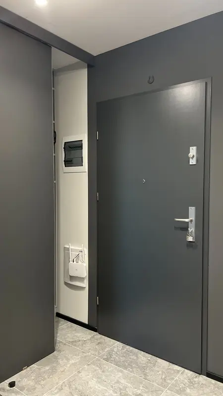 Nowoczesny przedpokój w soft minimalizmie z szarymi ścianami i współczesnymi detalami.