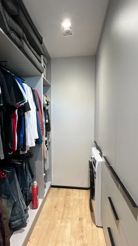 Garderoba w stylu nowoczesnym i soft minimalizm, z szarymi szafkami i drewnianą podłogą.
