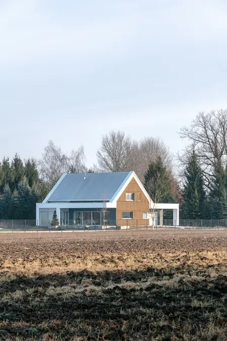 Nowoczesny dom z drewnianą elewacją i dużymi oknami pośród natury.