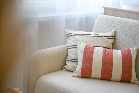Sofa w stylu japandi z poduszkami w paski i jasnym tłem.