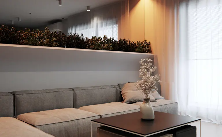 Eklektyczny minimalistyczny salon z szarymi meblami i roślinami.