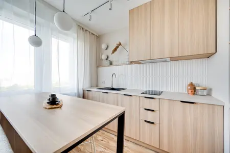 Wnętrze kuchni w stylu japandi z drewnianymi meblami i białymi detalami.