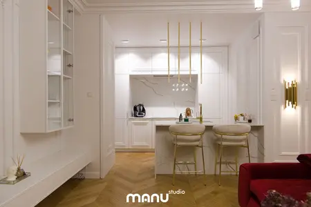 Wnętrze kuchni w stylu nowoczesnym z białymi meblami i złotymi detalami.