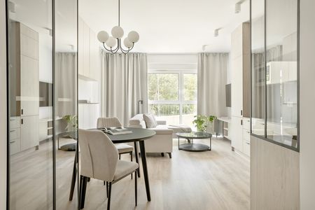 Wnętrze nowoczesnego salonu z minimalistycznym designem, jasnymi meblami i roślinnością.