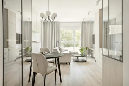 Wnętrze nowoczesnego salonu z minimalistycznym designem, jasnymi meblami i roślinnością.