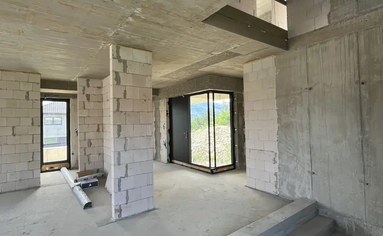 Wnętrze budynku z betonowymi ścianami i dużymi oknami, nowoczesny design.