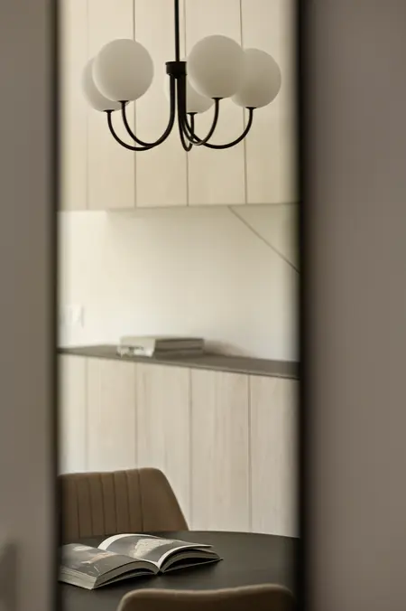 Wnętrze jadalni z okrągłym stołem, minimalistycznym stylem i nowoczesnym oświetleniem.