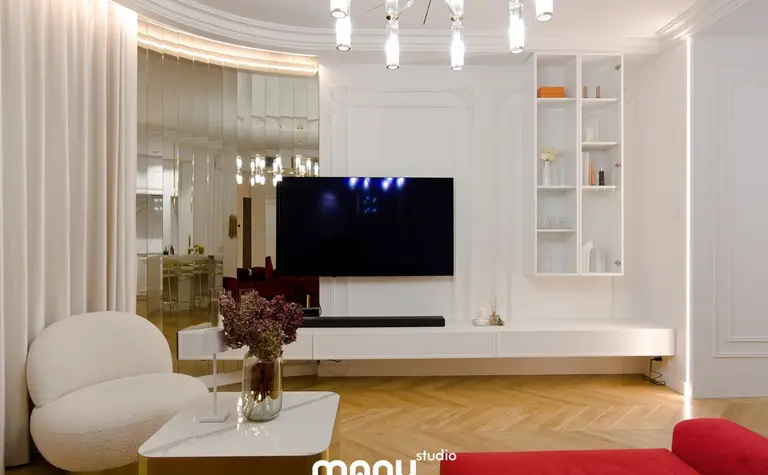 Wnętrze salonu z białymi meblami, nowoczesnymi akcentami i tradycyjnym oświetleniem.