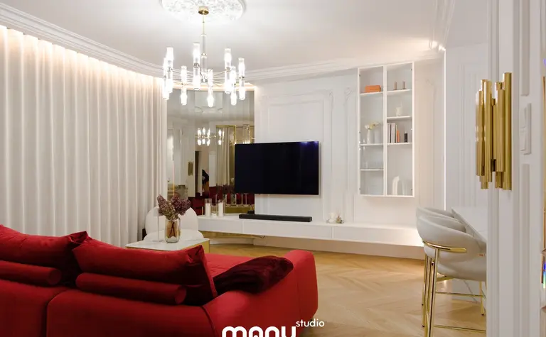 Wnętrze salonu z nowoczesnym oświetleniem, czerwonymi sofami i minimalistycznym wystrojem.