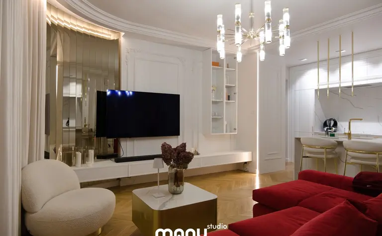 Wnętrze salonu z czerwonymi meblami, nowoczesnym oświetleniem i tradycyjnymi detalami.