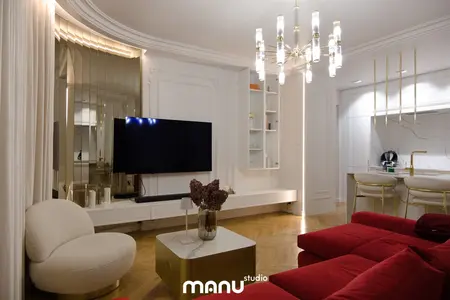 Wnętrze salonu z czerwonymi meblami, nowoczesnym oświetleniem i tradycyjnymi detalami.