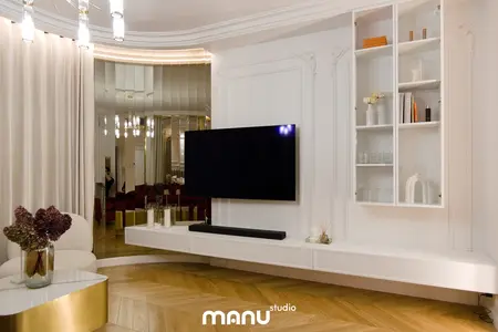 Wnętrze salonu z białymi meblami, drewnianą podłogą i lustrem.