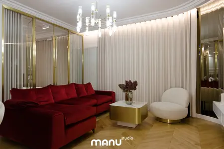 Wnętrze salonu z czerwonymi meblami, złotym stolikiem i nowoczesnymi detalami.