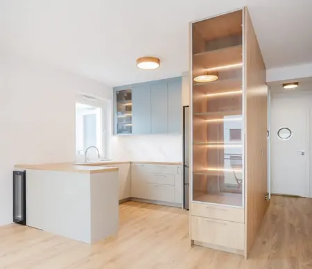 Nowoczesna kuchnia z niebieskimi meblami i drewnianym blatem, minimalistyczny design.