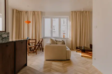 Wnętrze salonu w stylu quiet luxury, soft minimalizm i vintage z beżową sofą i drewnianymi akcentami.