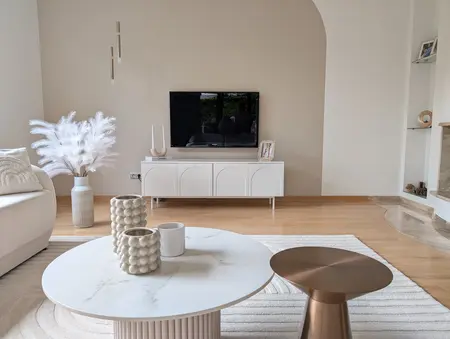 Wnętrze salonu minimalistycznego z białą sofą i nowoczesnym telewizorem.