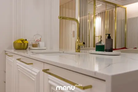 Nowoczesna łazienka z białą umywalką i złotymi elementami, tradycyjny design.