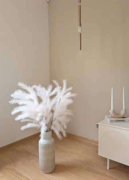 Wnętrze z minimalistycznym wystrojem, białymi dekoracjami i drewnianym podłogą.