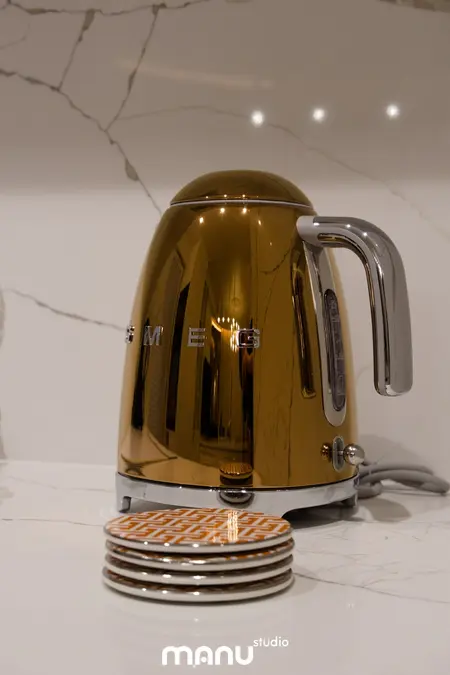 Czajnik SMEG w kolorze miedzianym na marmurowym blacie w nowoczesnej kuchni.
