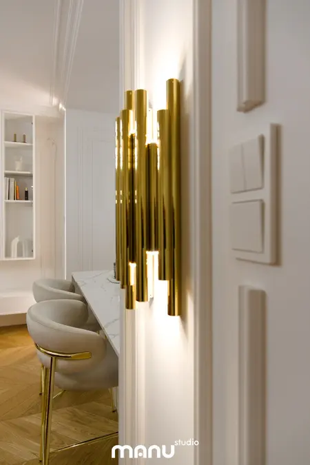 Złote oświetlenie w nowoczesnym wnętrzu z białymi meblami. Styl quiet luxury i tradycyjny.