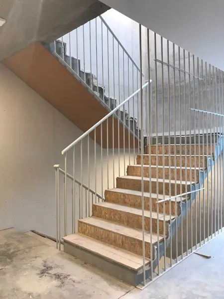 Wnętrze industrialne z białymi schodami i betonowymi ścianami.
