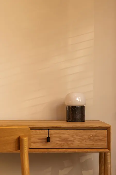 Minimalistyczne biuro z drewnianym biurkiem i nowoczesną lampą.