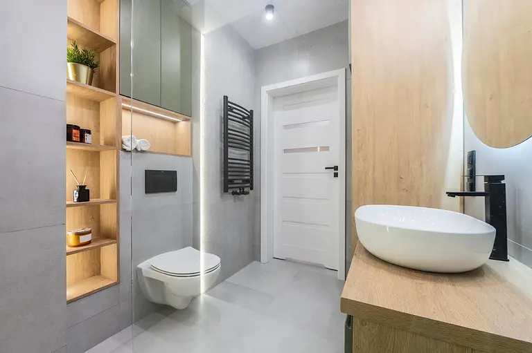 Wnętrze łazienki z drewnianymi meblami i nowoczesnymi detalami w stylu industrialnym i współczesnym.