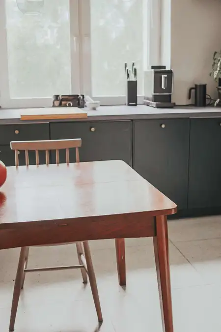 Eklektyczne wnętrze kuchni z drewnianym stołem i nowoczesnymi akcesoriami.