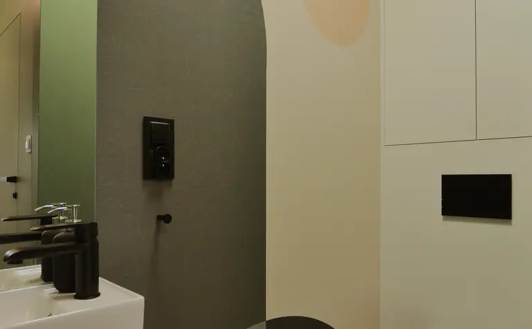Toaleta z minimalistycznym wystrojem, ściana w odcieniach zieleni i beżu.
