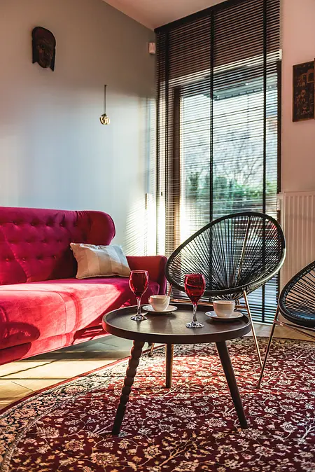 Wnętrze salonu z różową sofą, czarnymi fotelami i stołem kawowym w stylu eklektycznym.