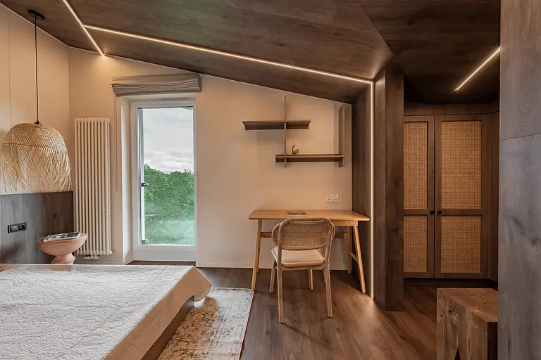 Wnętrze poddasza w stylu boho i skandynawskim z drewnianymi meblami i jasnymi akcentami.
