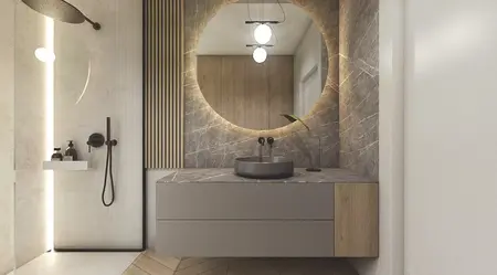 Wnętrze nowoczesnej łazienki z okrągłym lustrem, szarymi meblami i detalami w stylu soft minimalizm.