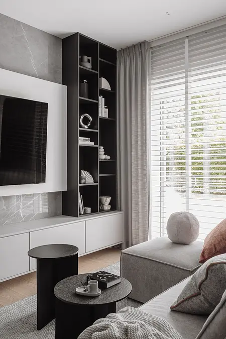 Wnętrze salonu z szarym narożnikiem i czarnymi stolikami, nowoczesny design.