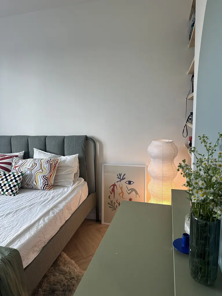 Sypialnia w stylu boho, eklektycznym i skandynawskim z szarym łóżkiem i kolorowymi akcentami.
